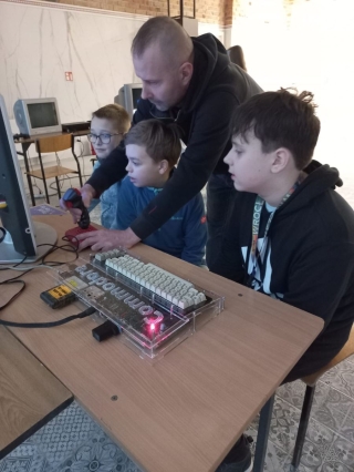 uczniowie 5b oglądają sprzęt komputerowy z lat 80-tych